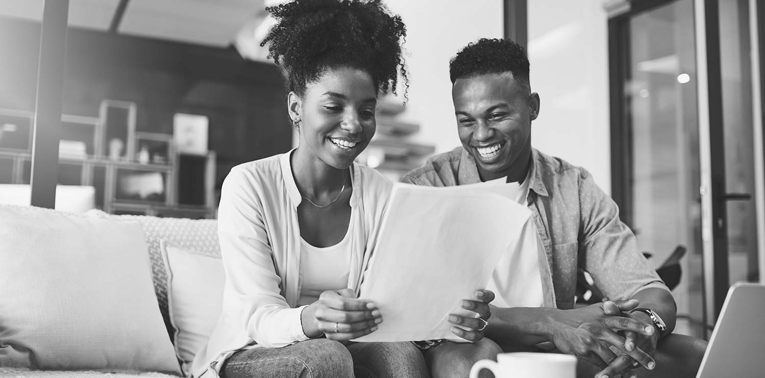 Two people smiling and looking at papers